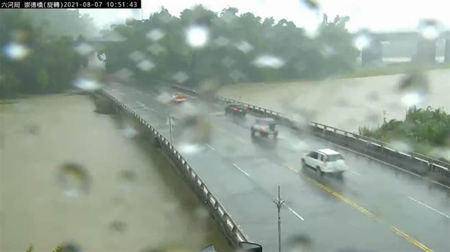 高雄昨夜降雨不断，位于田寮区二仁溪上的崇德桥，水面暴涨几乎快与桥面齐平，截至上午10时50分许依旧有不少人车冒雨通行。（图翻摄自YT／水利署水利防灾中心）