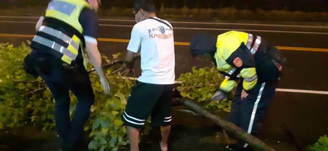 員警與熱心民眾帶兩把鋸子，冒大雨共同將樹木鋸斷後搬離車道，已恢復行車安全。（照片由霧峰警分局提供）