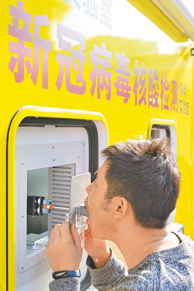 大陆湖北出动首辆移动核酸检测车支援全民检测。图为日前广东省广州市核酸自动检测车，车内的口腔咽拭子採样机器人自动採样。（中新社）