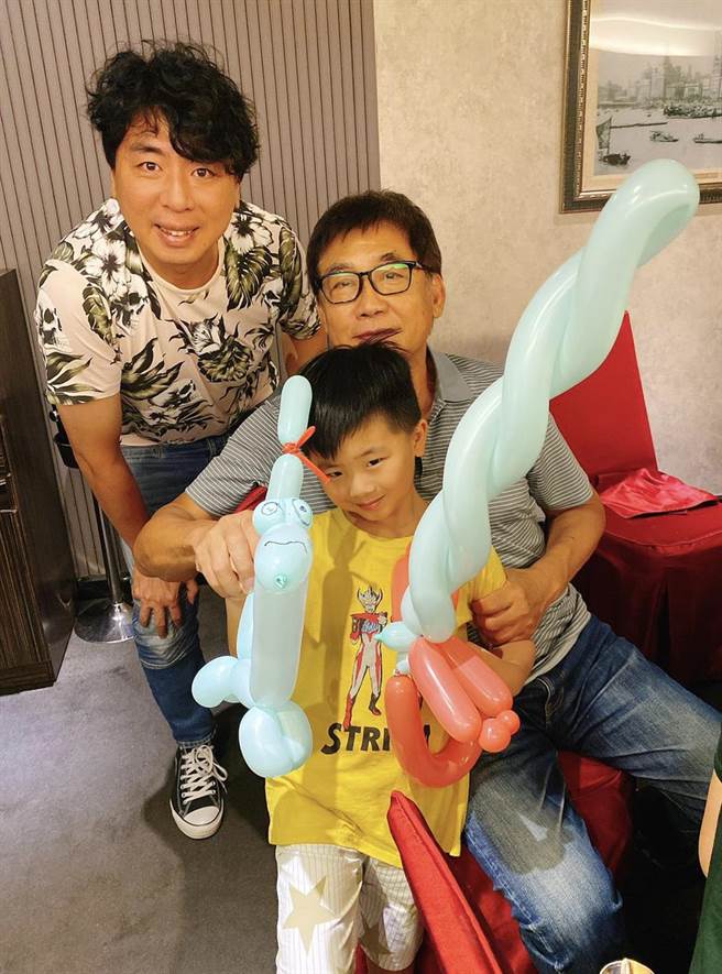 梁修身为孙子小宝学折气球，儿子梁赫群眼红（梁修身提供）