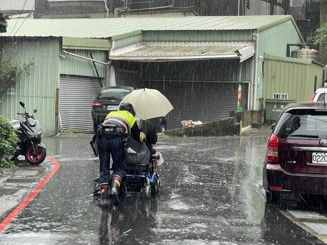 杨姓男子昨天受困雨中，所幸暖心警察协助推他回家。（警方提供）