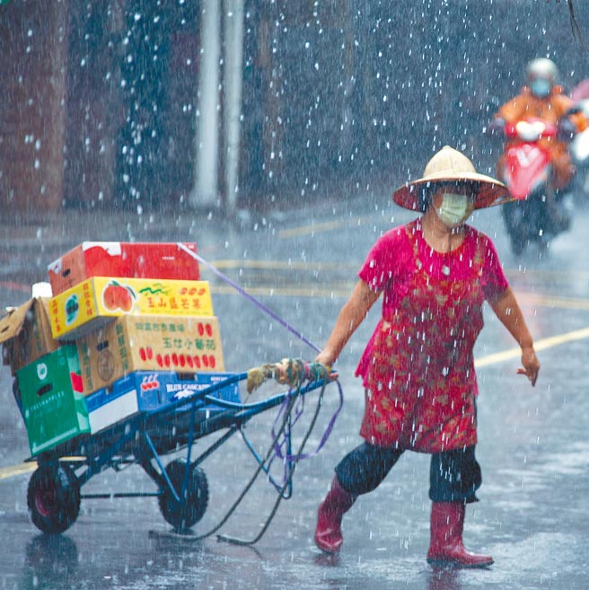 全国受疫情影响，即使防疫警戒降至2级，行政院规画推出「振兴5倍券」，刺激内需消费，商家仍冒着大雨为生计努力。（罗永铭摄）