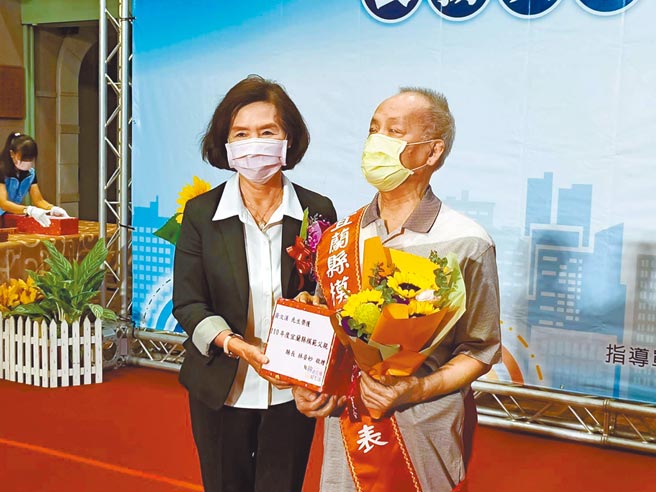 宜蘭縣三星鄉民眾黃文漢（圖右）年輕時因疾病導致全盲，一度對人生失去希望，和同為盲人的妻子經營按摩店，克服了人生困境，將一對子女拉拔長大，不向命運屈服的故事及精神感動許多人，7日獲宜蘭縣長林姿妙（圖左）表揚為模範父親。（胡健森攝）