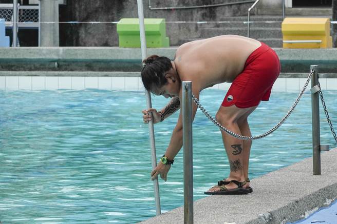 泳池工作人员手持工具清理户外泳池壁面。（黄子明传真）