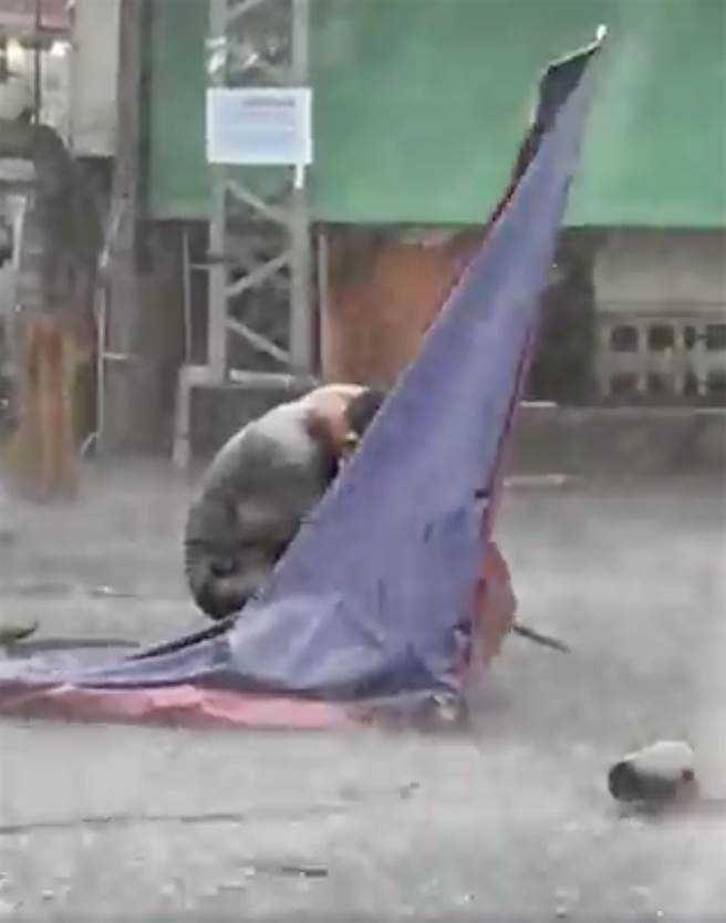 台中市下午3点半左右，突然来了一阵狂风暴雨，水像用倒的一样，道路立即积水，一位民眾拍下，一位摊商与大雨搏斗的情况。（翻摄自大里人聊天室脸书／黄国峰台中传真）