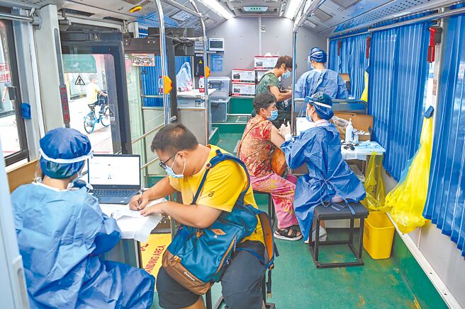 「中國疾病預防控制中心周報」日前公布研究指出，在高溫天氣下，將會分散民眾對防疫的警惕，持續戴口罩的行為減少了20.6％。圖為9日廣州市民在由公車改建成的接種站內接種新冠疫苗。（中新社）