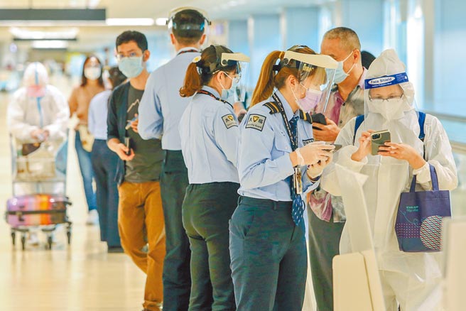 中央流行疫情指挥中心10日公布国内新增8例COVID-19确定病例，分别为3例本土及5例境外移入。图为桃园机场入境旅客在入关前，先拿出手机展示，让CDC协勤人员核视相关健康声明检疫资料。（陈麒全摄）