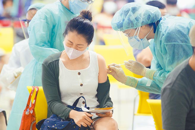 国民党立委林奕华连日来追查第二类「生产、仓储和物流人员」遭疑特权接种疫苗争议，卫福部长陈时中昨公布数据，指「疫苗生产及仓储物流人员」共2614人接种，其中高端和联亚仅4人。图为台北花博接种站，为补教专案人员施打疫苗，有民眾接种时表情痛苦。（张铠乙摄）