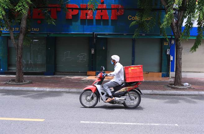 一名送货员骑着机车经过越南已关闭的商店。（美联社）