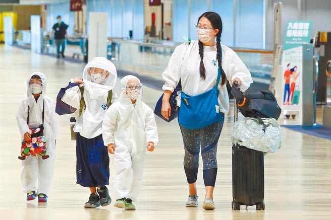 国内11日新增16例确诊，分别为12例本土及4例境外移入；另确诊个案中新增2例死亡，4例境外移入个案。图为桃园机场一位入境旅客带着3个孩童，所有人都身穿防护衣全副武装。（陈麒全摄）