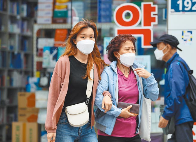圖為戴口罩的市民走在韓國首爾的街道上。（新華社）