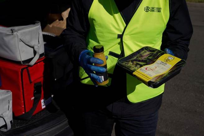 雪梨单日新增染疫人数再创新高。图为澳洲人员向民眾发送食物。（图／路透社）
