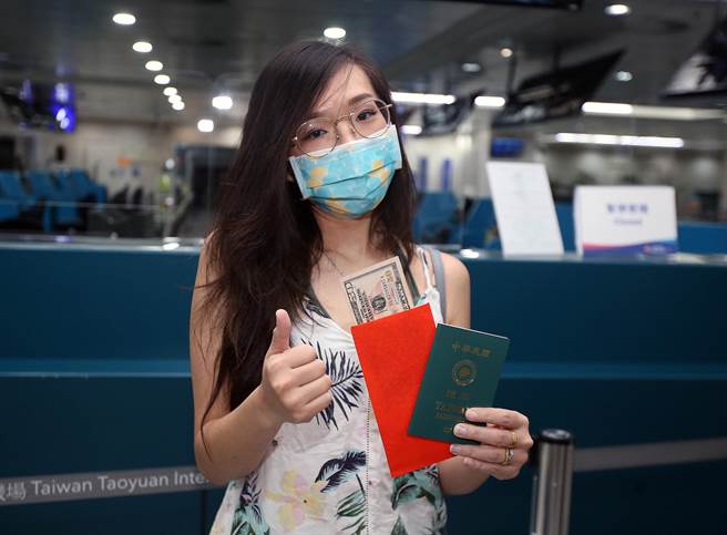 旅客开心地展示帛琉政府赠送的美金50元红包。（范扬光摄）