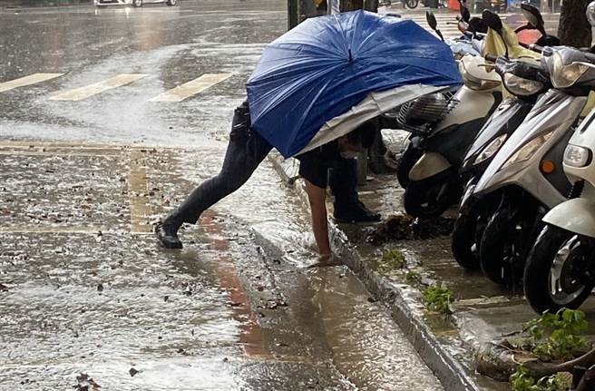 高雄警见积水，徒手挖开树枝、树叶疏通排水孔。(图／左营分局提供)