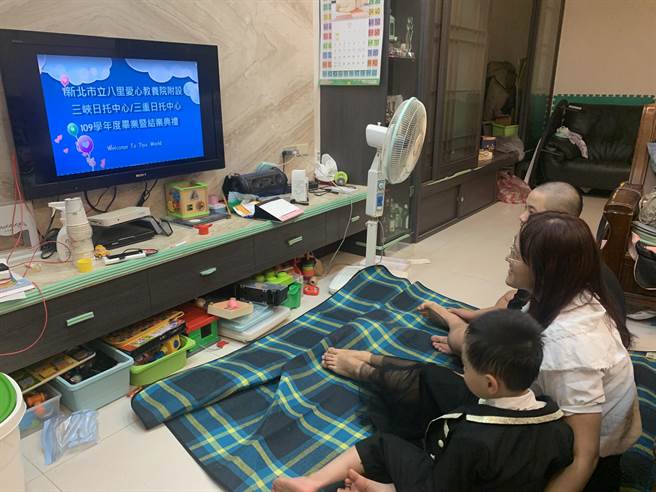 翔翔盛裝打扮，在家和媽媽一起觀看線上直播畢業典禮。（社會局提供）