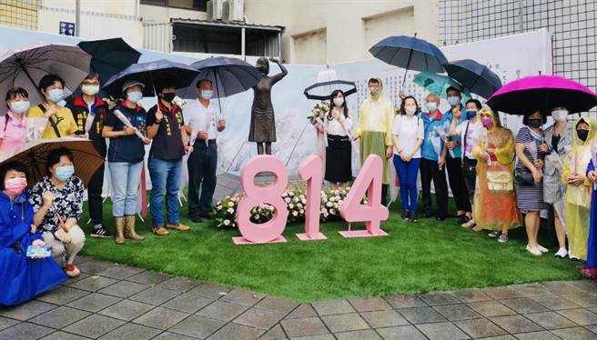 国民党副秘书长谢龙介（中间黄色雨衣者）、台南市慰安妇人权平等促进会理事长童小芸（中间白衣黑裙者）与眾人一起在慰安妇铜像前下献花追思。（国民党台南市党部提供／程炳璋台南传真）