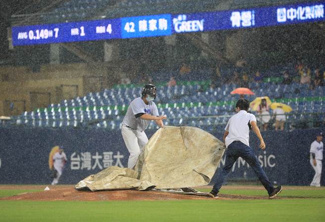 富邦悍将14日对战中信兄弟，2局上比赛因大雨暂停，工作人员将内野区盖上帆布。（张铠乙摄）