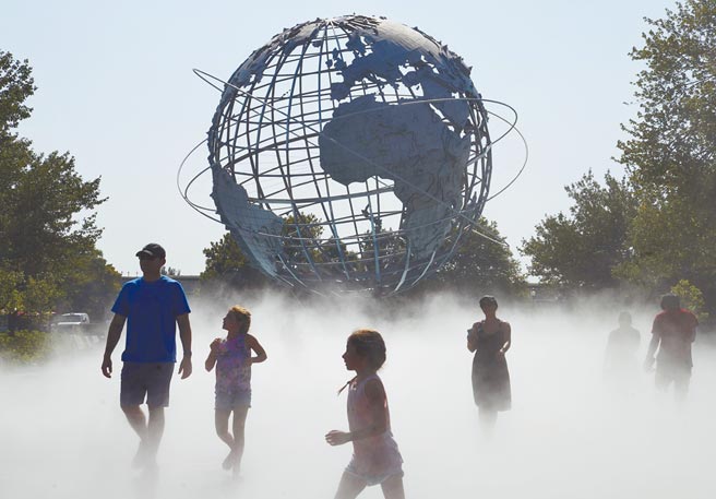 美國紐約市連日來遭遇高溫天氣。圖為8月13日，民眾在紐約科羅納公園的水霧廣場，享受清涼一刻。（新華社）