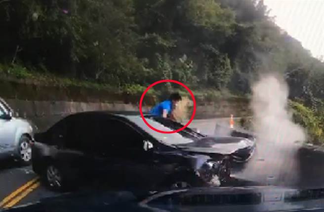 黑色轎車自撞護欄後狂冒白煙，一名藍色上衣男子迅速下車跳下護欄往山谷逃逸。（截自影像）