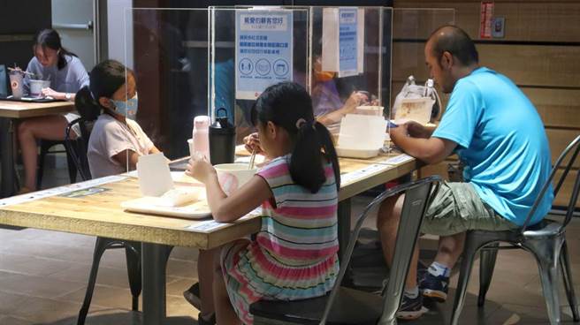 新冠肺炎疫情趨緩，疫情警戒降至2級，也放寬餐飲規範，不過卻有4歲小孩用餐時被要求自己吃個人鍋，引發爭議。中央流行疫情指揮中心19日宣布同住家人共餐規範將放寬。圖為小朋友與家人依防疫規範隔開用餐。（王英豪攝）