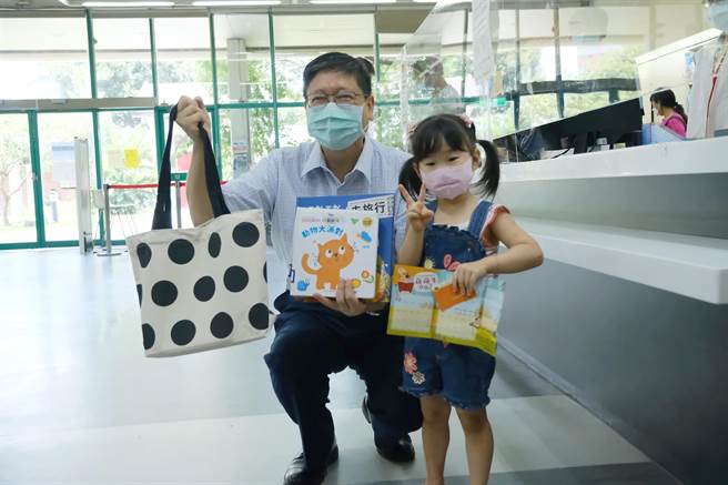 新竹縣長楊文科（左）20日前往文化局圖書館，帶著孩子示範領取閱讀禮袋的流程。（莊旻靜攝）