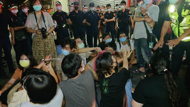 学生被绑上束带，抬离墙下，聚集在马路上静坐，警方团团包围。（程炳璋摄）