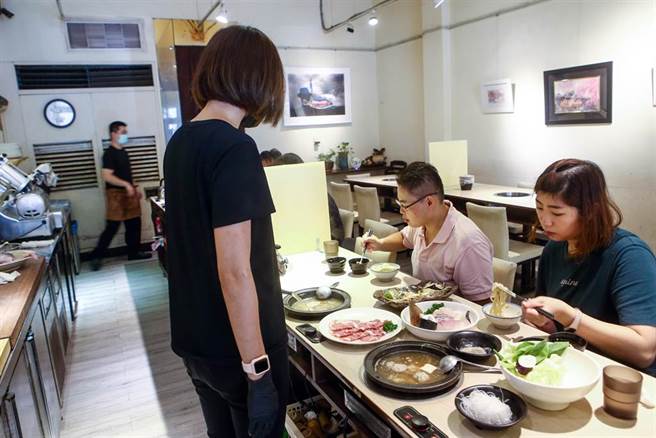 時序雖已進入立秋，但中午仍天氣炎熱，許多民眾在週休二日時外出用餐，進入有冷氣的火鍋店，吃著火鍋也讓身體的熱氣冒出。中央疫情指揮中心日前宣布，二級警戒再延長到9月6日和多項鬆綁措施，除了同住親友可在餐廳免隔板共餐外，也無需梅花座、專人分菜。（鄧博仁攝）
