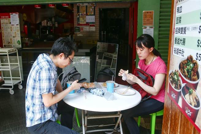 中央疫情指揮中心日前宣布，二級警戒再延長到9月6日和多項鬆綁措施，除了同住親友可在餐廳免隔板共餐外，也無需梅花座、專人分菜。假日的台北街頭，有民眾坐在騎樓享用早午餐。（鄧博仁攝）
