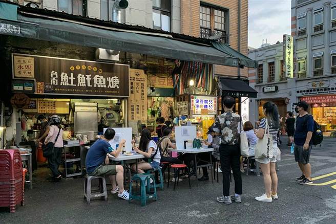 中央疫情指揮中心日前宣布，二級警戒再延長到9月6日和多項鬆綁措施，除了同住親友可在餐廳免隔板共餐外，也無需梅花座、專人分菜。假日的台北街頭，有民眾坐在戶外用餐區，享受美食。（鄧博仁攝）
