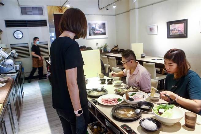 時序雖已進入立秋，但中午仍天氣炎熱，許多民眾在週休二日時外出用餐，進入有冷氣的火鍋店，吃著火鍋也讓身體的熱氣冒出。中央疫情指揮中心日前宣布，二級警戒再延長到9月6日和多項鬆綁措施，除了同住親友可在餐廳免隔板共餐外，也無需梅花座、專人分菜。（鄧博仁攝）