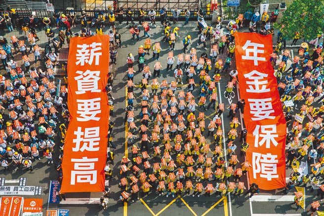 劳保未提存负债达10.8兆，学者推估，若劳保破产后全数以公务预算支应，政府每年恐要编列逾4000亿、超过国防预算。图为今年五一大游行，劳工拉布条表达诉求。（本报资料照片）