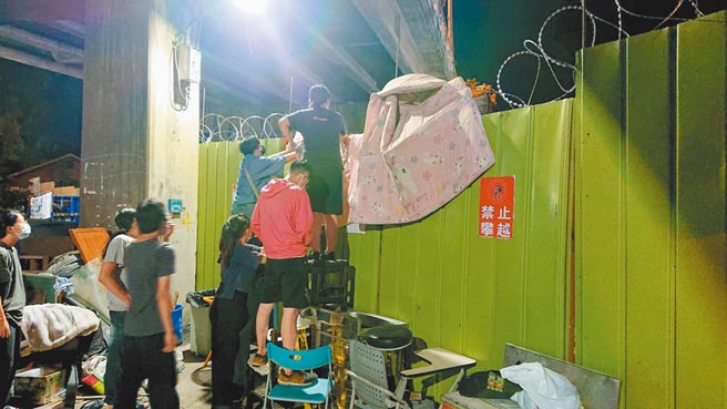 聲援學生與民眾在鐵絲網鋪棉被欲越過圍籬，要求鐵道局停止拆除黃春香家。（程炳璋攝）