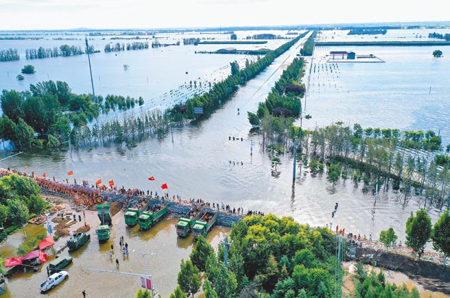 河南将面临新一波强降雨，因此宣布自21日12时起，启动防汛Ⅱ级应急响应。图为河南省鹤壁市浚县傅庄堤上，不少群眾自发前来和救援人员一起装沙袋、运沙袋，共筑堤坝。（新华社）