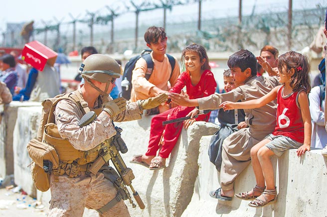 在喀布爾國際機場，一名美軍陸戰隊士兵正與等候撤離阿富汗的孩子們一起玩耍。（摘自美國國防部官方臉書）