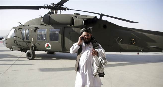 一名男子2017年10月7日在阿富汗坎达哈机场（Kandahar Airport）UH-60M「黑鹰」（Black Hawk）直升机前打手机的资料照。（美联社）