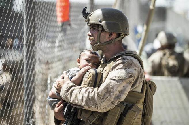 美军陆战队在阿富汗喀布尔机场掩护撤退行动时，抱着一名当地幼儿。（图／美军陆战队、美联社）