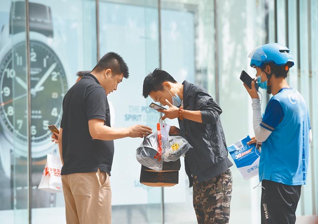 截至6月，中国网上外卖用户规模达4.69亿，增长4976万，在各类调查应用中增速最为明显。图为外卖送餐员在北京一处办公大楼外与顾客交接餐食。（中新社资料照片）