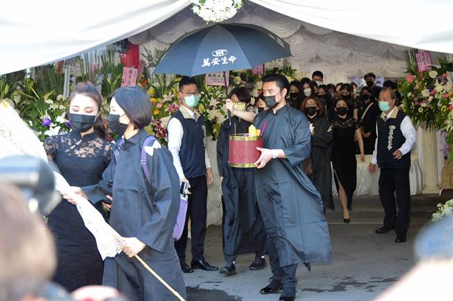 李㼈面容哀戚手捧父亲牌位。（林淑娟摄）