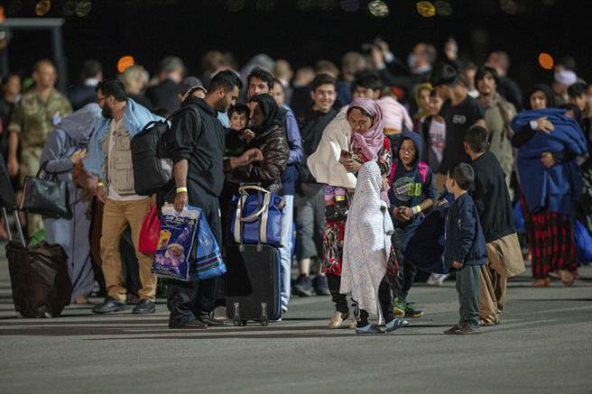 這架撤離難民的飛機搭載111人，其中乘員主要是婦女和小孩，他們攜帶隨身行囊走在停機坪。(圖／美聯社)