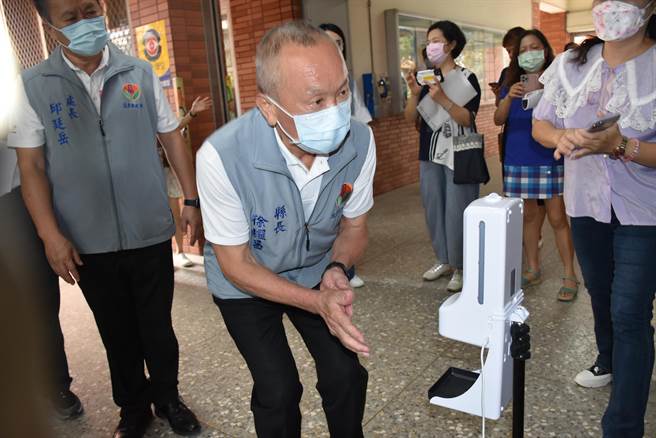 苗栗縣長徐耀昌特蹲低身體測試幼兒園入口體溫檢測酒精噴灑器功能。（謝明俊攝）