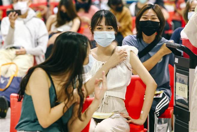 开学即将到来，新进专任教师、代理代课教师、实习教师等教育相关工作人员，30日前往花博接种站施打COVID-19（2019冠状病毒疾病）疫苗，赶在中、小学9月1日开学前完成施打。一位刚接种完毕的民眾，回头比着ok，安抚同行施打人员。（邓博仁摄）
