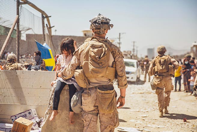 图为一个美国海军陆战队在阿富汗喀布尔的哈米德卡尔扎伊国际机场照顾一名年轻女孩。（摘自美国国防部官方推特）