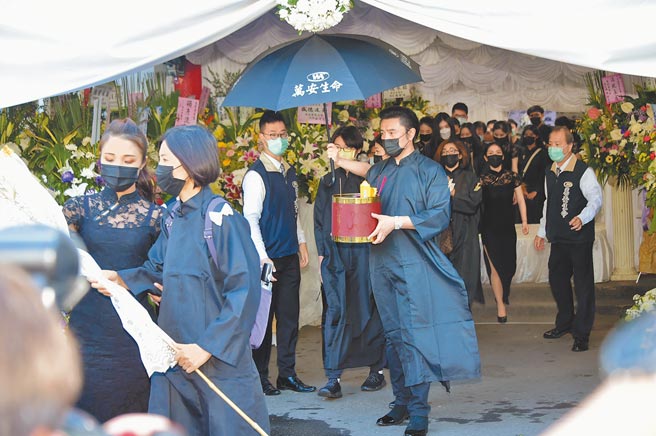 李㼈在父亲告别式上手捧牌位。（林淑娟摄）