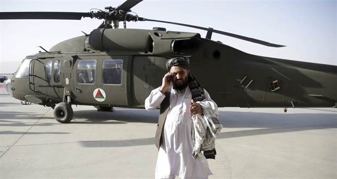 一名男子2017年10月7日在阿富汗坎达哈机场（Kandahar Airport）UH-60M「黑鹰」（Black Hawk）直升机前打手机的资料照。（美联社）