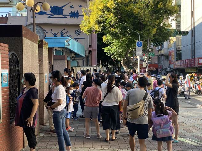 许多家长在孩子入校后仍依依不舍的望着孩子的背影。（游念育摄）