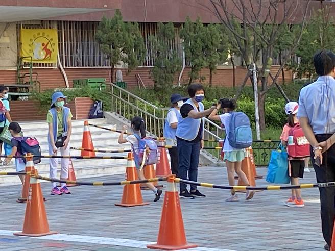 石牌国小校门口的行政人员一早就战战兢兢，量体温动线并加开量体温动线加速放流。（游念育摄）
