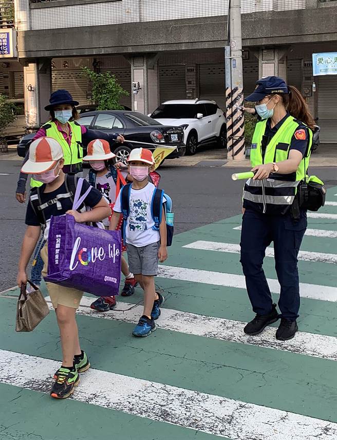 开学了，中市警局雾峰分局启动护童勤务，员警协同各校的导护老师及志工，引导学童通过马路。（雾峰分局／黄国峰台中传真）