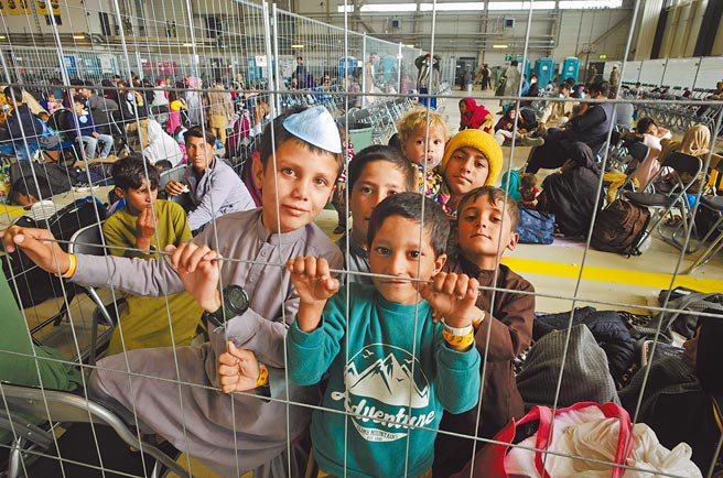 在德国拉姆斯坦美军空军基地所搭建的临时出境室内，一群阿富汗小孩与其他阿富汗人一起等候撤离前往美国或其他国家。美国使用这个空军基地，作为运送阿富汗撤离人员前往各地的枢纽。（美联社）