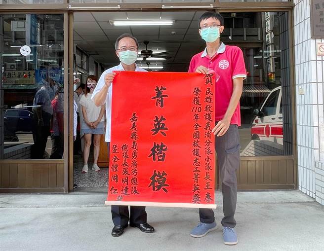 民雄乡乡长何嘉恒等人前往民雄消防分队张贴红榜，向王春仁道贺。（嘉义县消防局提供∕吕妍庭摄）