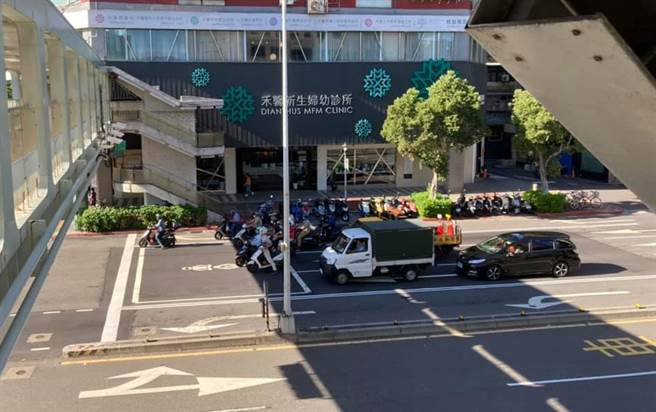 1名网友日前在台北街头发现1处路口因上方陆桥造成地面有大片阴影，停等红灯的机车骑士为了躲太阳几乎都躲在该阴影处，形成前方停等区几乎没车的现象。（翻摄自脸书「路上观察学院」）